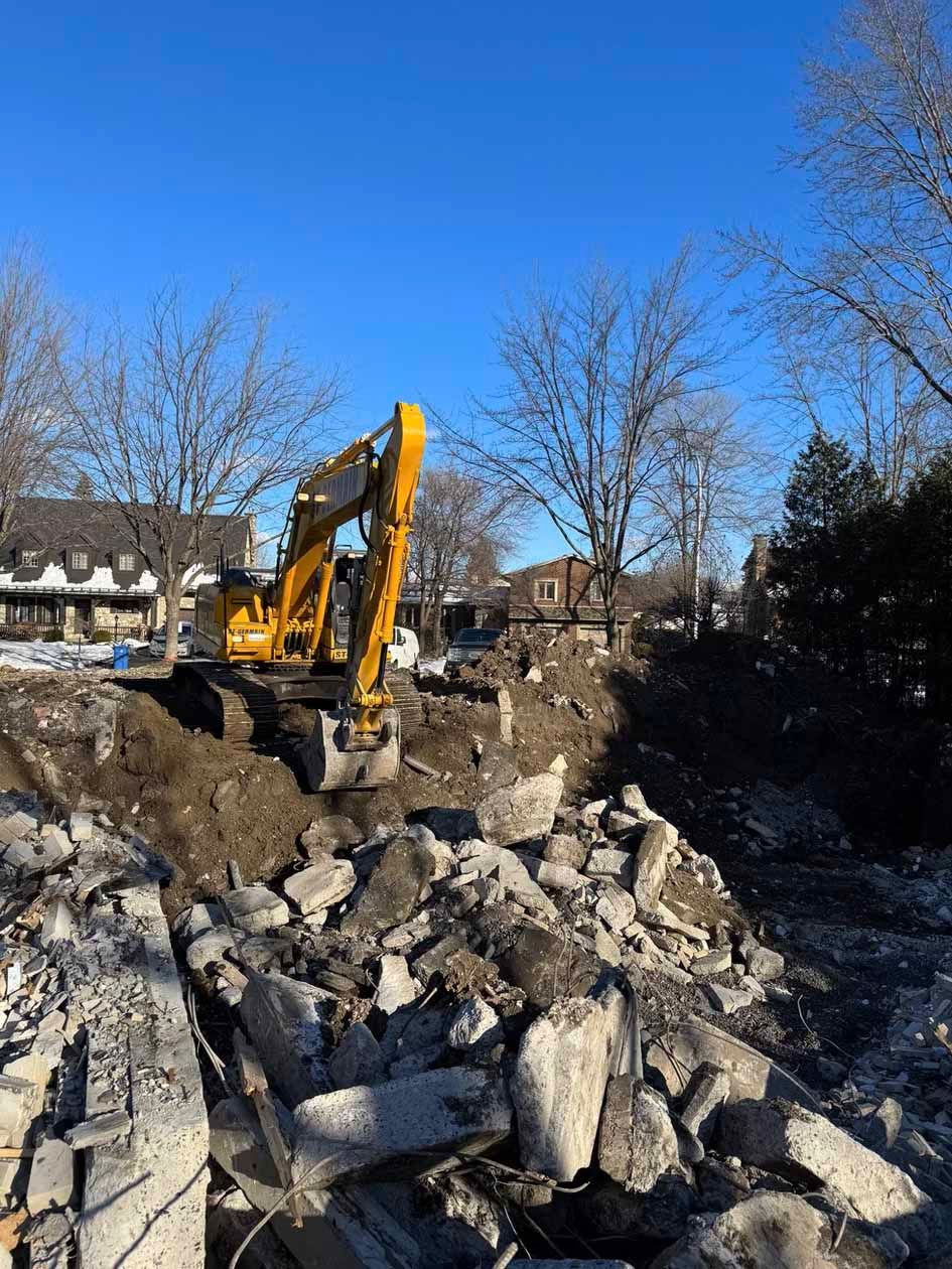 Une excavatrice jaune est assise sur un tas de rochers.