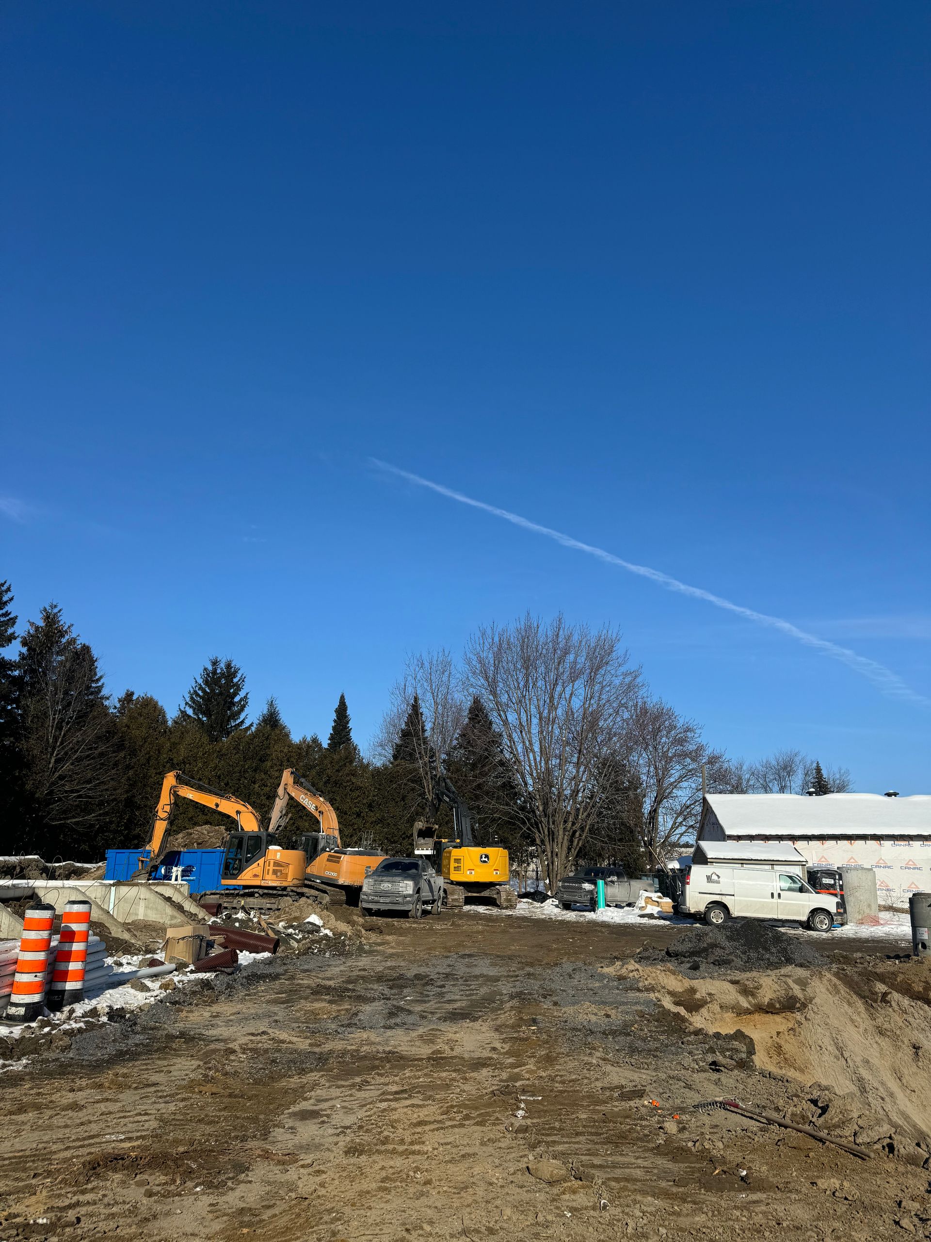 Un chantier avec beaucoup de camions et de tracteurs par une journée ensoleillée.