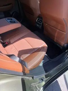 A close up of the back seat of a car with brown leather seats.