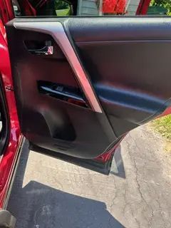 The back door of a red car with the door open.