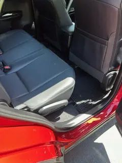 The back seat of a red car with blue seats.