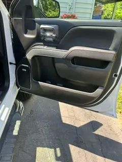 A white car with the door open is parked in a driveway.