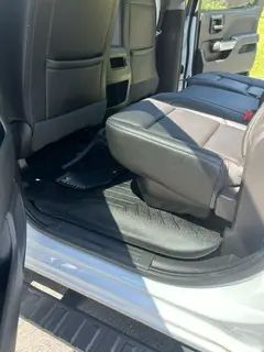 The inside of a white truck with the door open and the seats folded down.