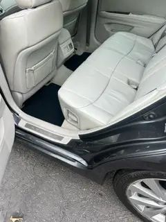 The back seat of a black car with white leather seats.