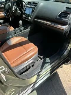 The interior of a car with the door open and brown leather seats.