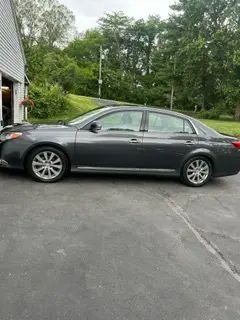 A gray car is parked in a driveway next to a garage.