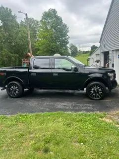 A black pickup truck is parked in a driveway in front of a house.
