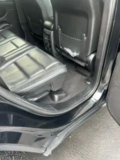 The back seat of a black car with the door open.