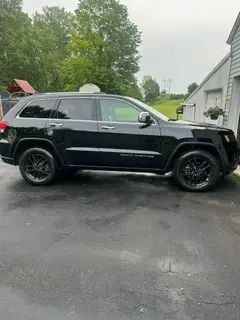 A black jeep grand cherokee is parked in a driveway next to a garage.