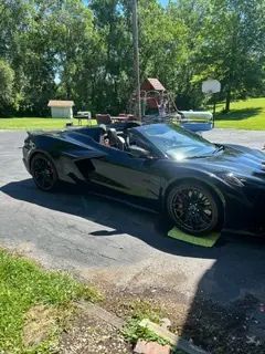 A black sports car is parked in a driveway next to a playground.
