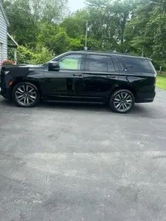A black suv is parked in a driveway next to a house.