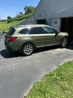 A green suv is parked in a driveway next to a garage.