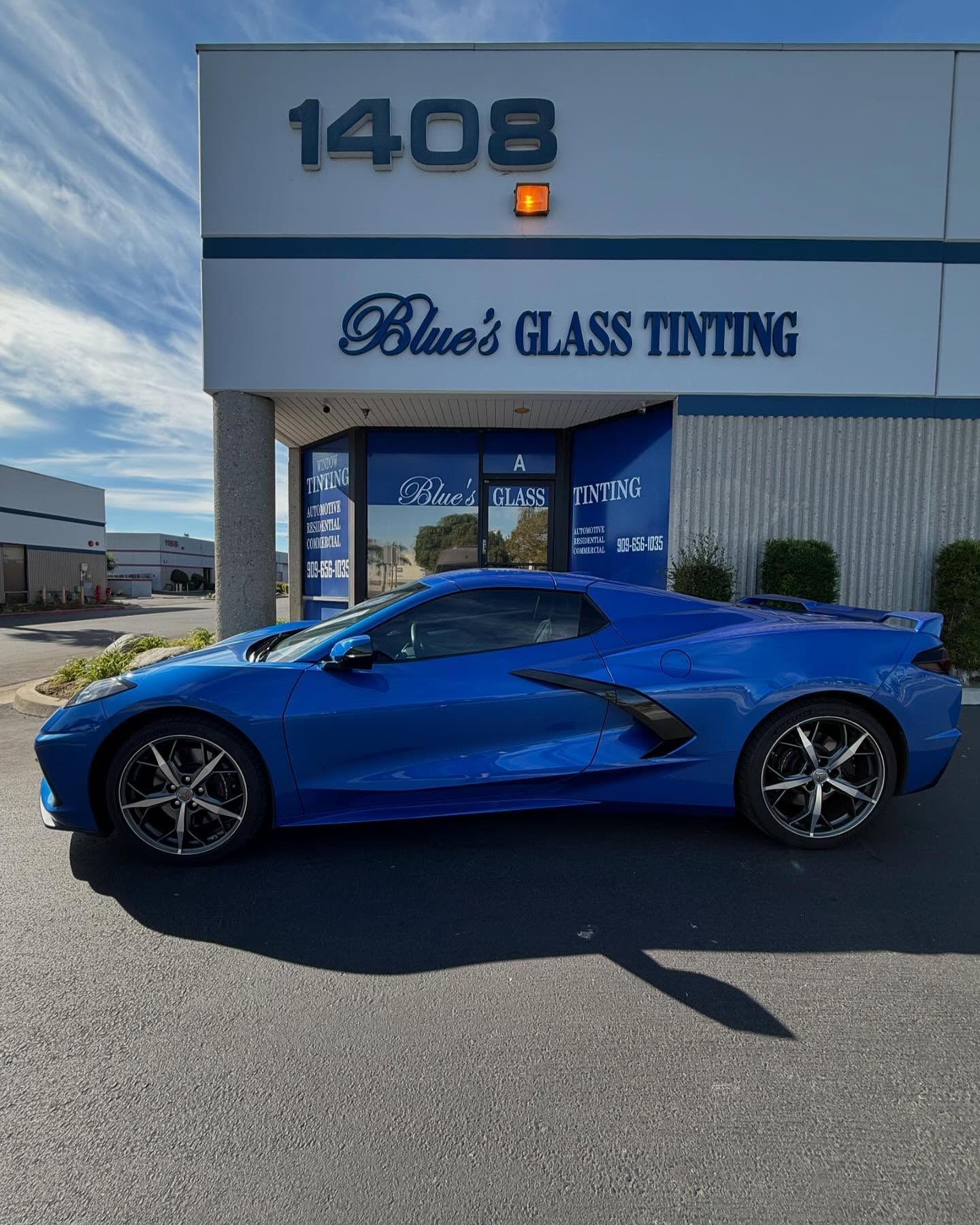Blue sports car parked outside a building labeled