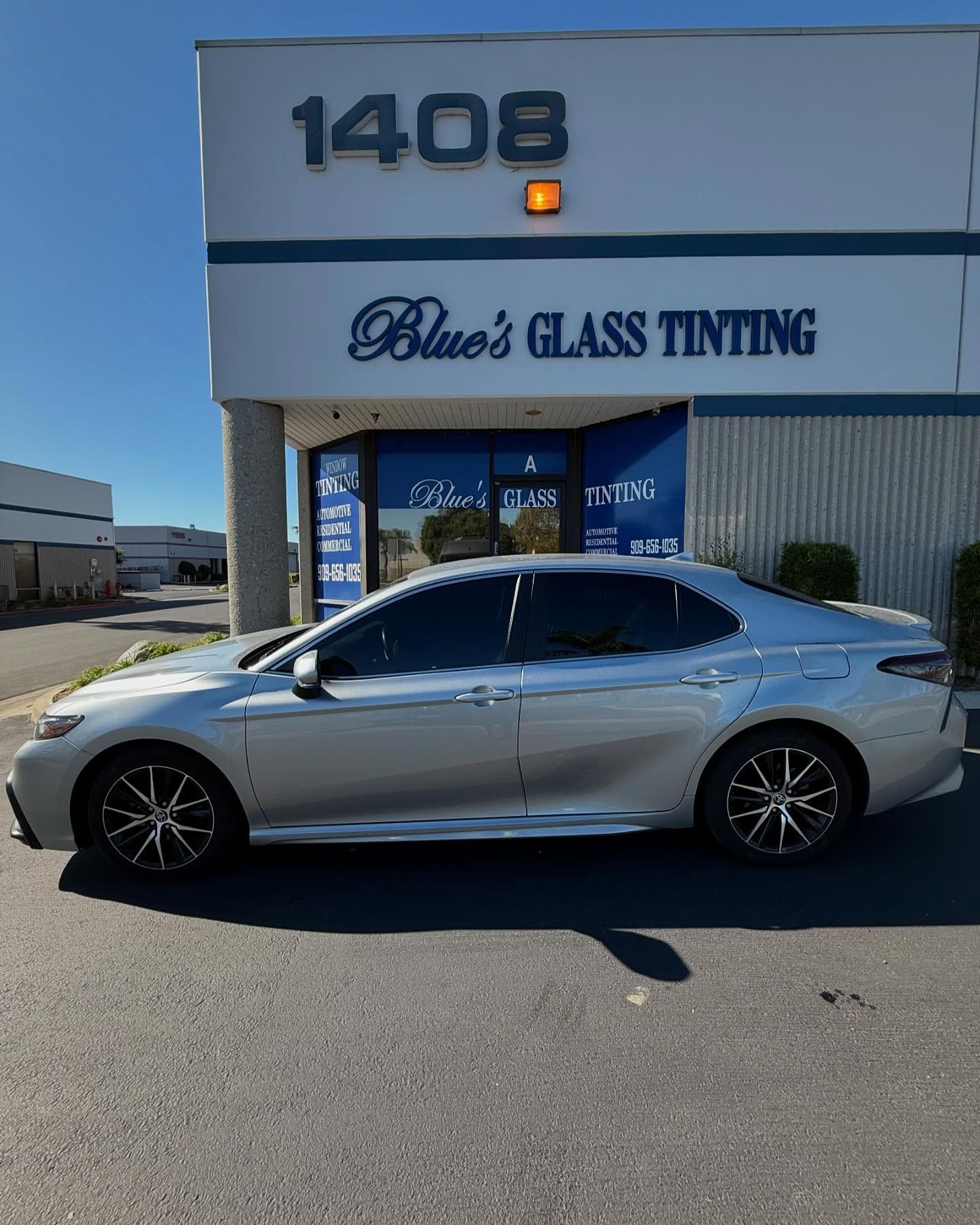 Silver car with tinted windows parked in front of a building labeled