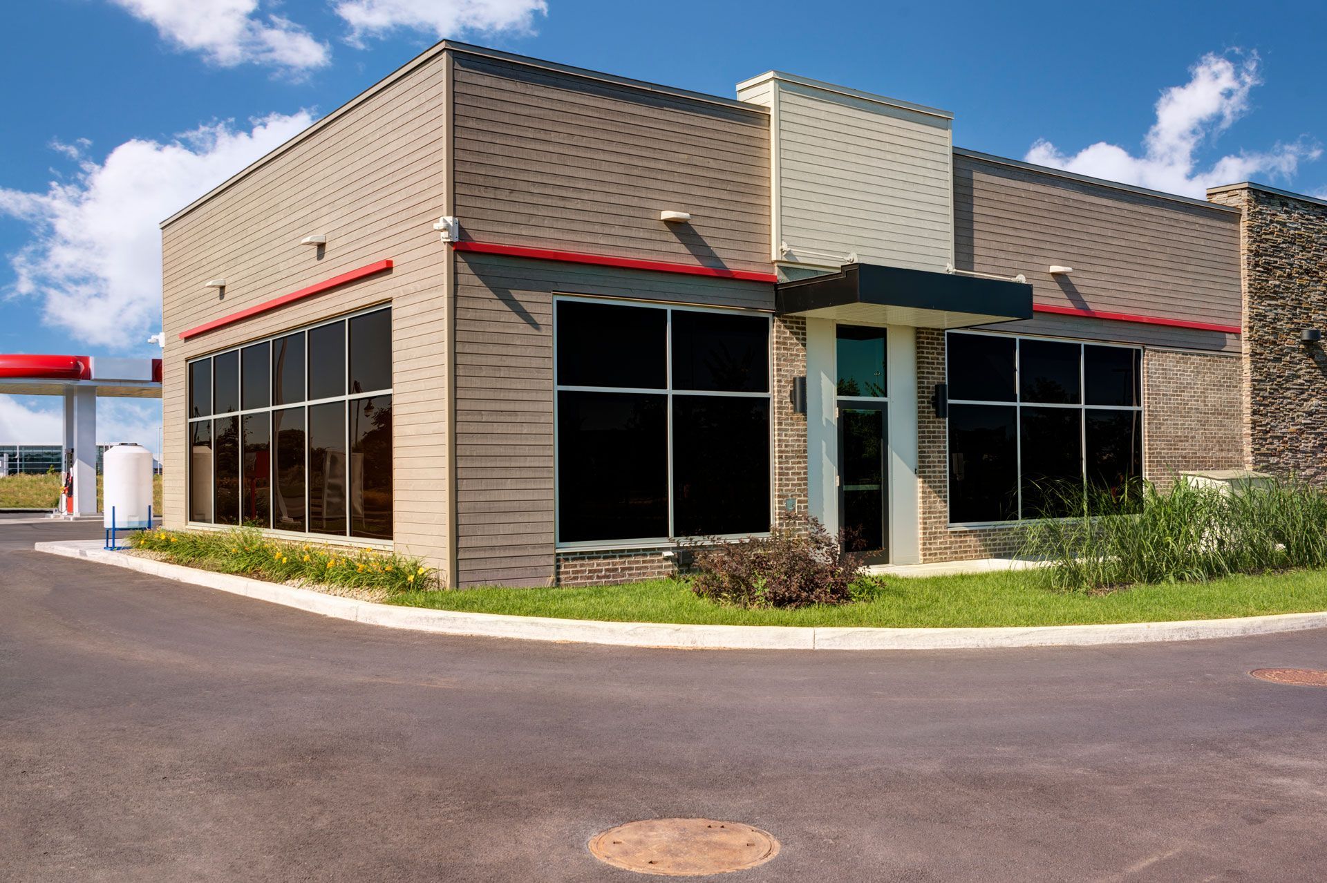Gas station convenience store with large tinted windows, brick exterior, and a red-trimmed roof.