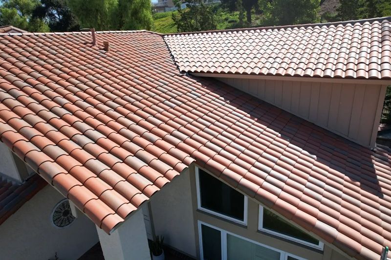 An aerial view of a residential house featuring terracotta-colored clay tile roofing and light-colored siding.