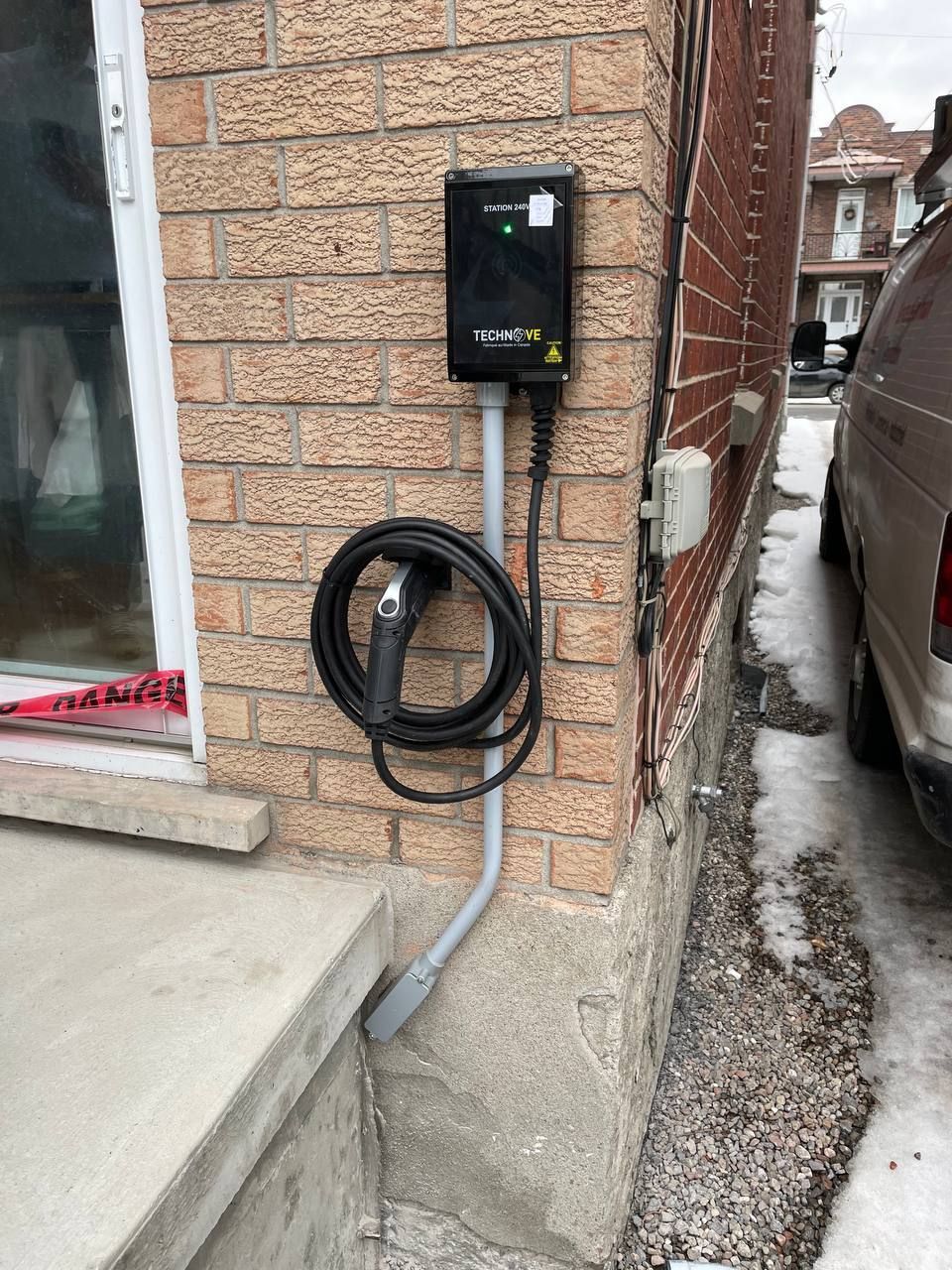 Un chargeur de voiture est fixé sur le côté d'un bâtiment en briques.