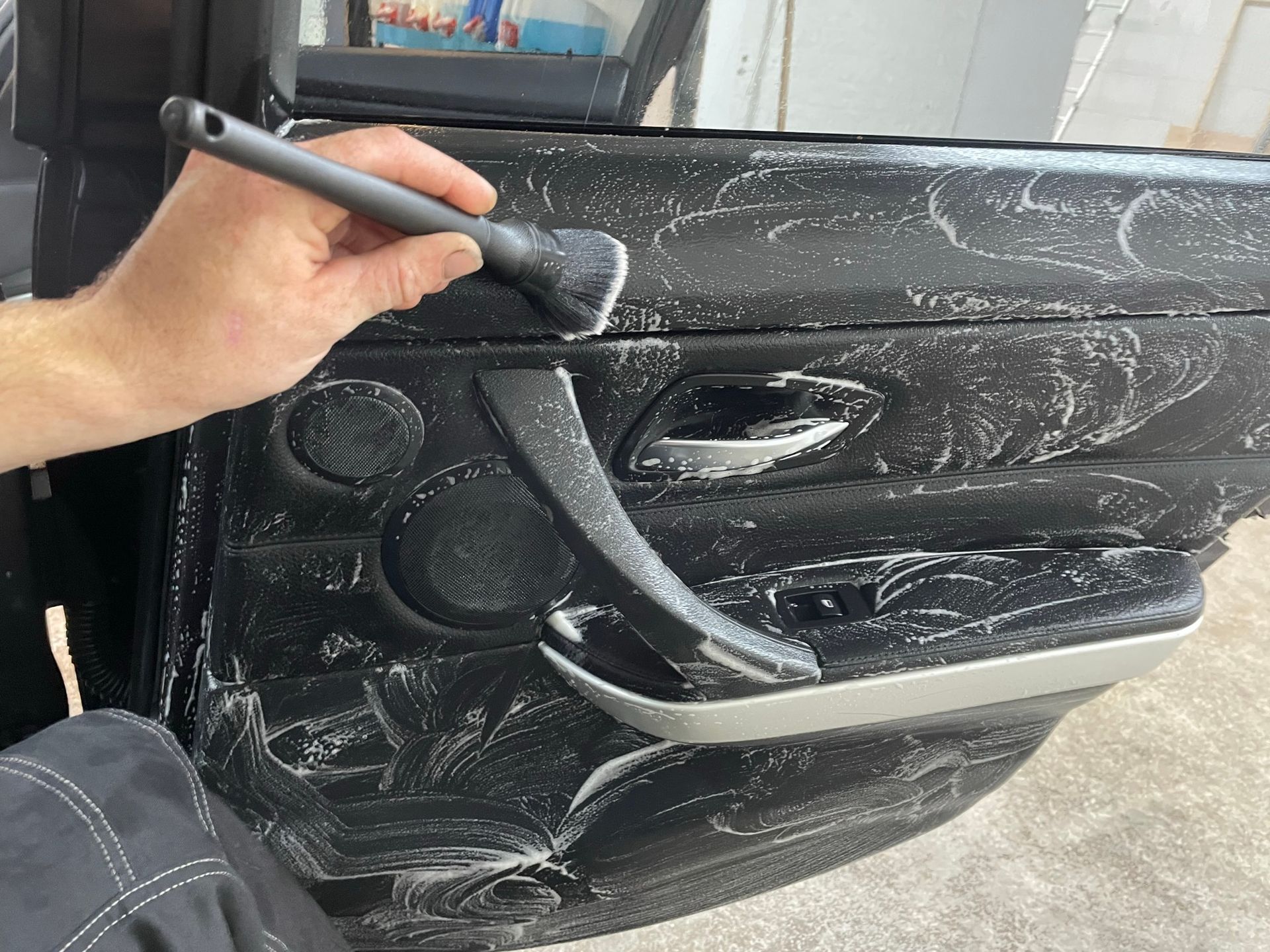 Een persoon maakt een autodeur schoon met een borstel.