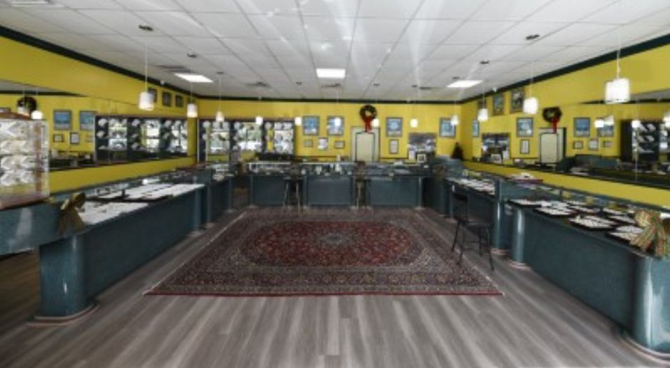 Jewelry store interior with display cases, yellow walls, and a patterned rug.