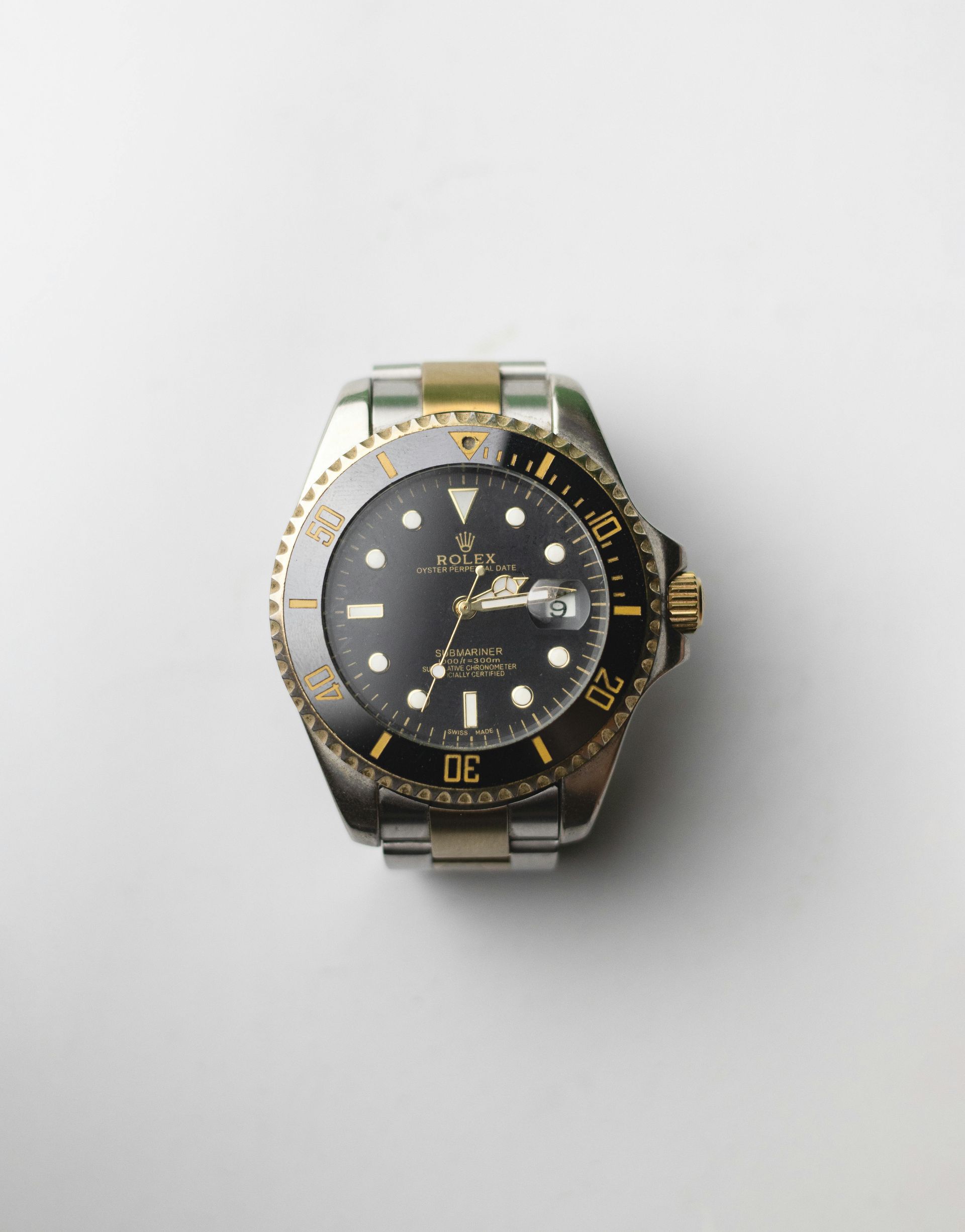Rolex Submariner watch with gold and silver accents on a white background.