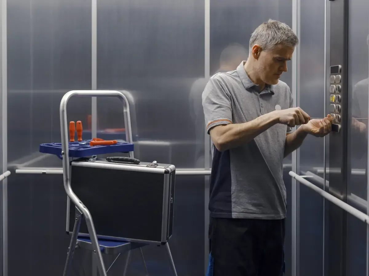 lift technician repairing elevator control panel inside lift