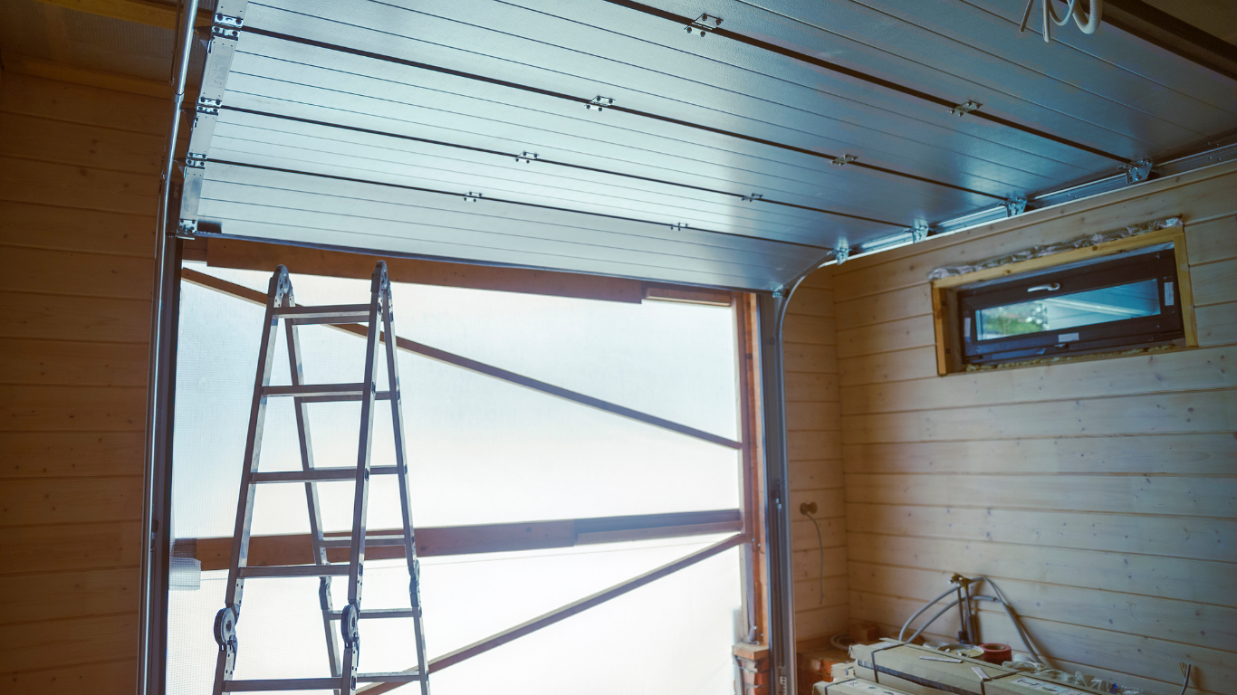 A ladder is sitting in a garage next to a garage door.
