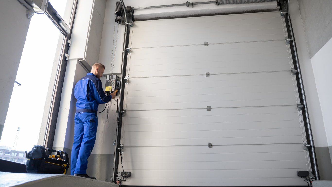 A man is working on a garage door in a garage.