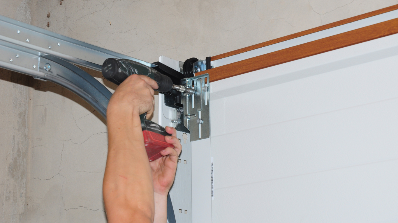 A person is fixing a garage door with a drill.