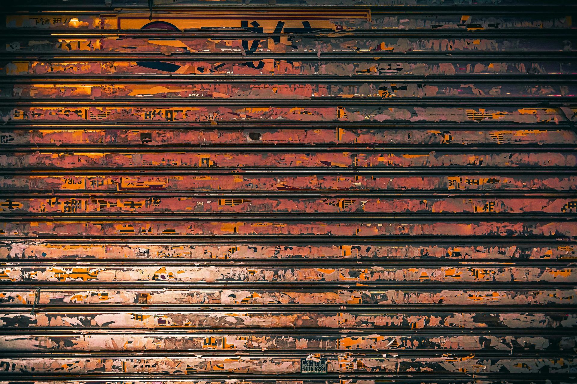 Weathered, rusty orange and brown metal security shutter; horizontal slats with peeling paint.