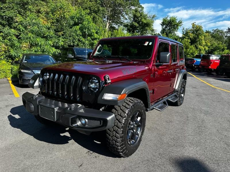 A red jeep wrangler is parked in a parking lot.