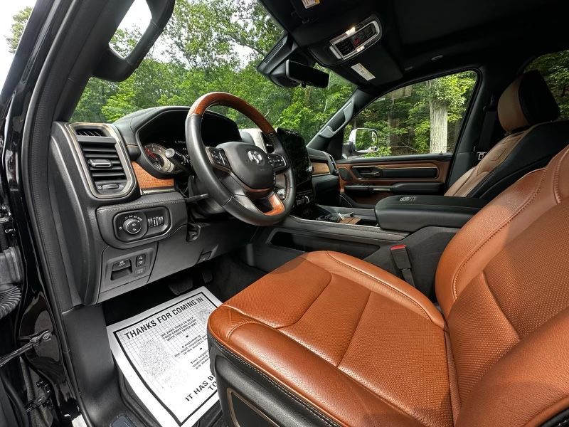 The interior of a ram truck with brown leather seats and a wooden steering wheel.
