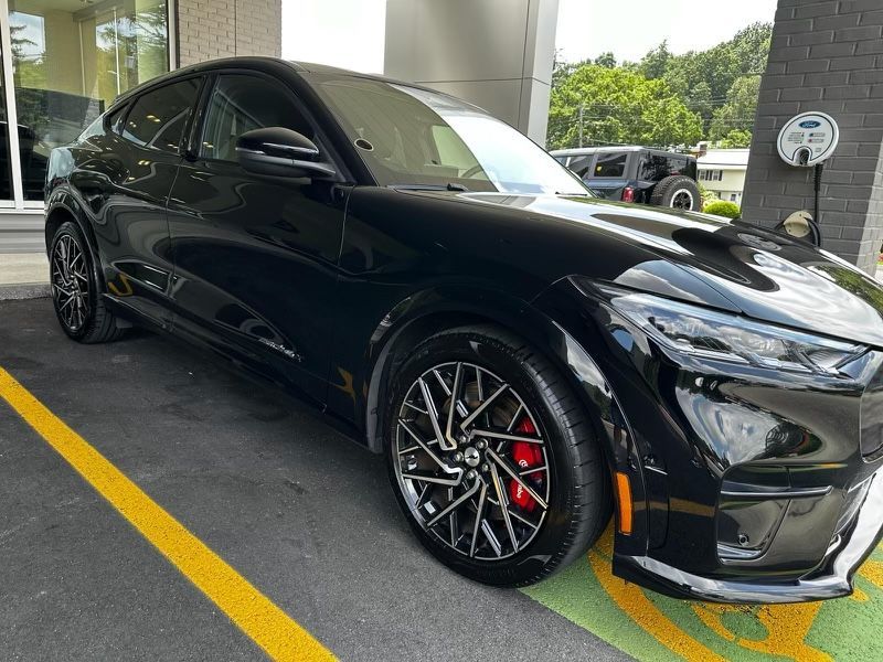 A black ford mustang mach e is parked in a parking lot.