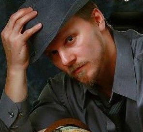 A man is holding a black and white dog in his arms.