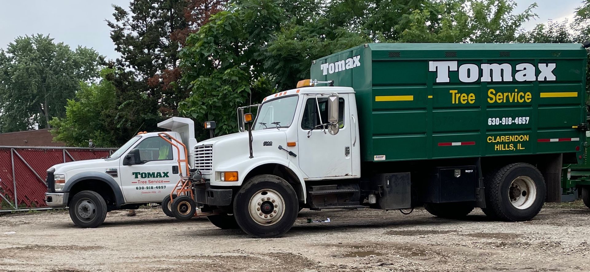Two tomax tree service trucks are parked next to each other