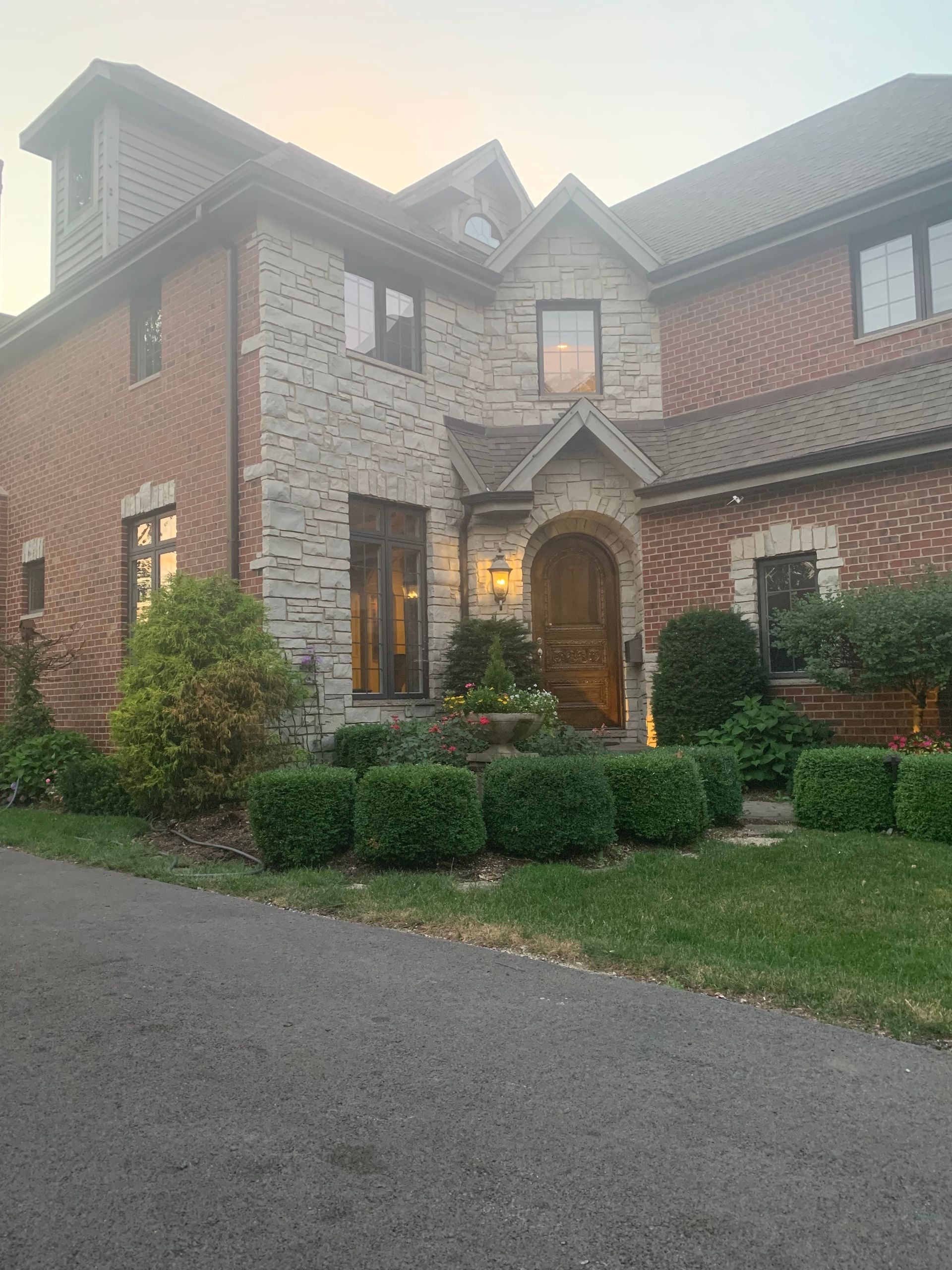 A large brick and stone house with a driveway in front of it.