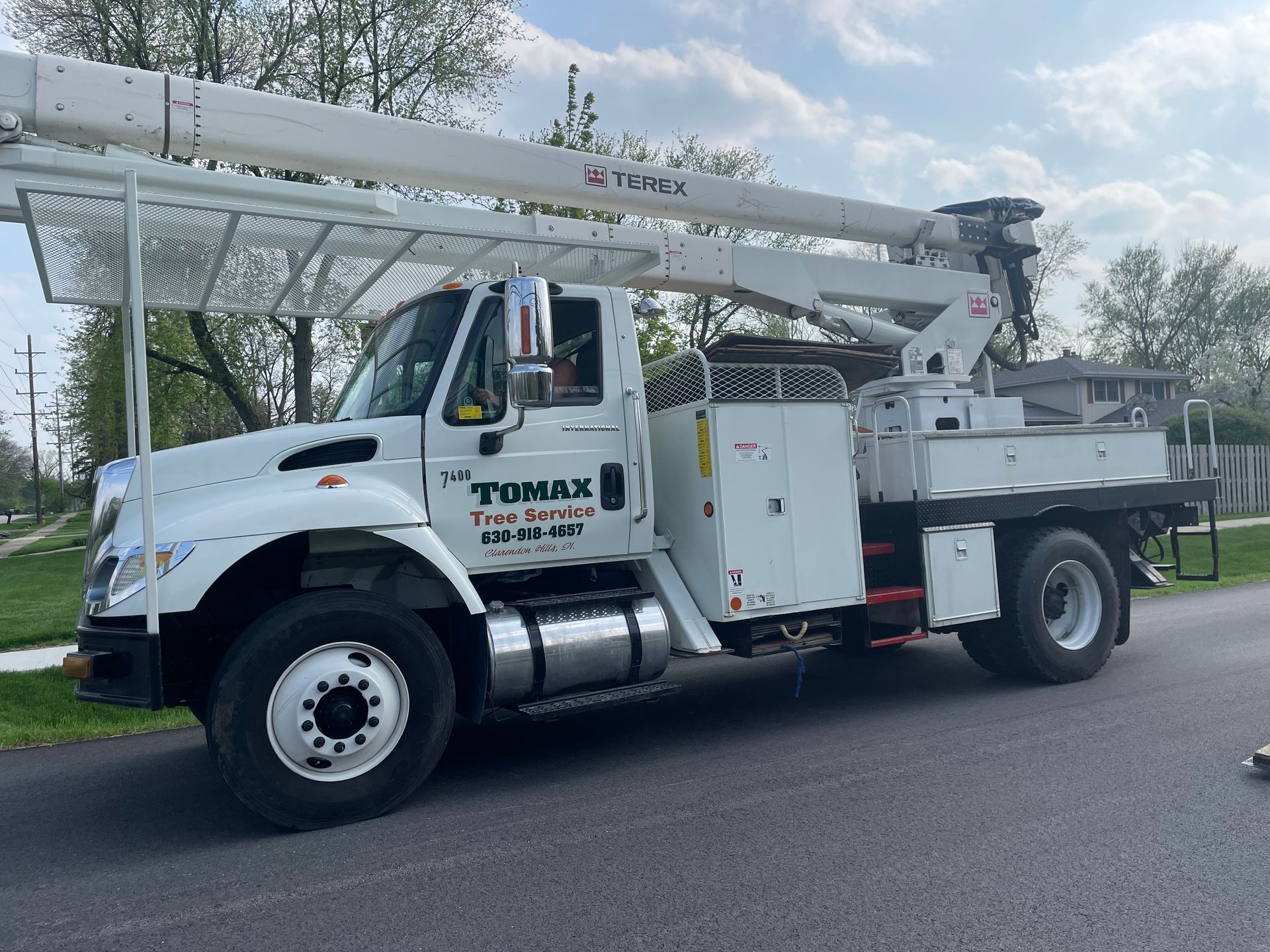 A white tumax truck is parked on the side of the road