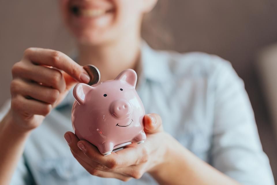 smiling woman puts a coin in a piggy bank as part of financial planning