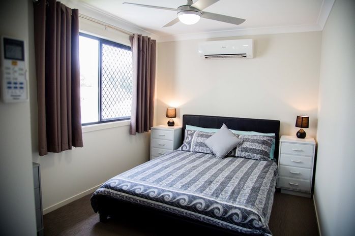 A bedroom with a bed , nightstands , and a ceiling fan — Integrabuild in Bowen, QLD