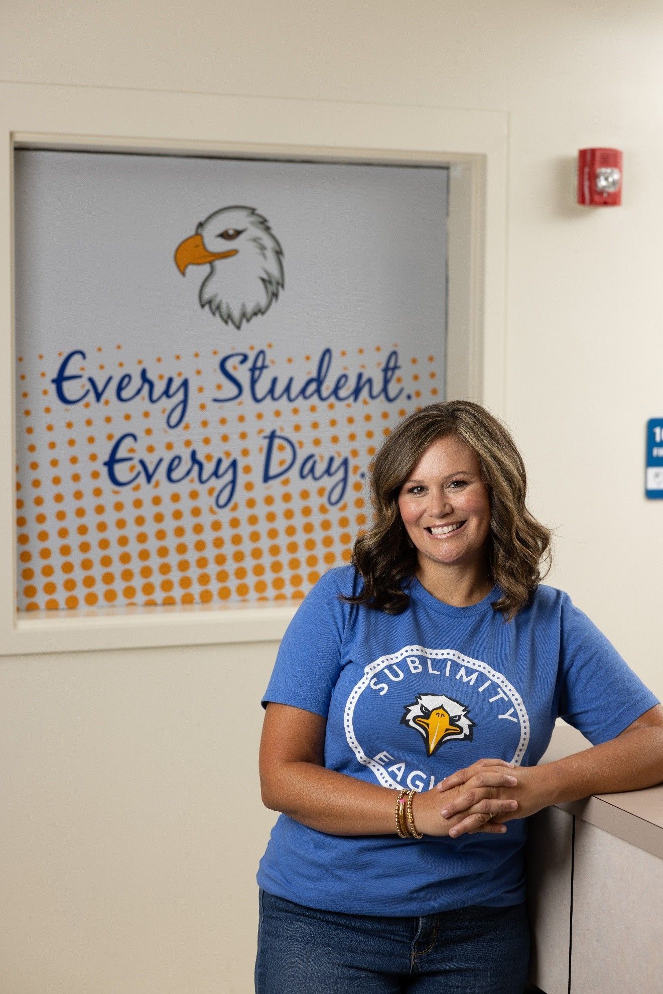 Woman in blue shirt smiles, leaning on counter; text
