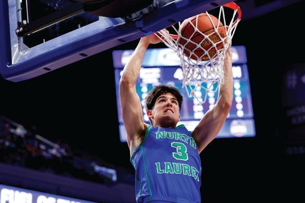 Basketball player in blue jersey dunks the ball into the hoop.