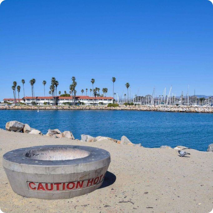 A caution hole sits in the sand near a body of water