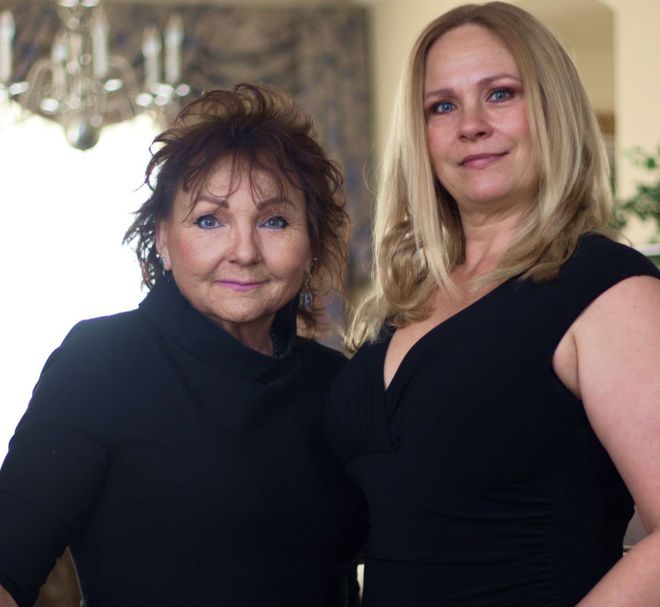 Two women are posing for a picture and one is wearing a black dress