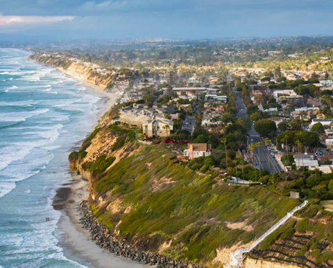 An aerial view of a city on a cliff overlooking the ocean.