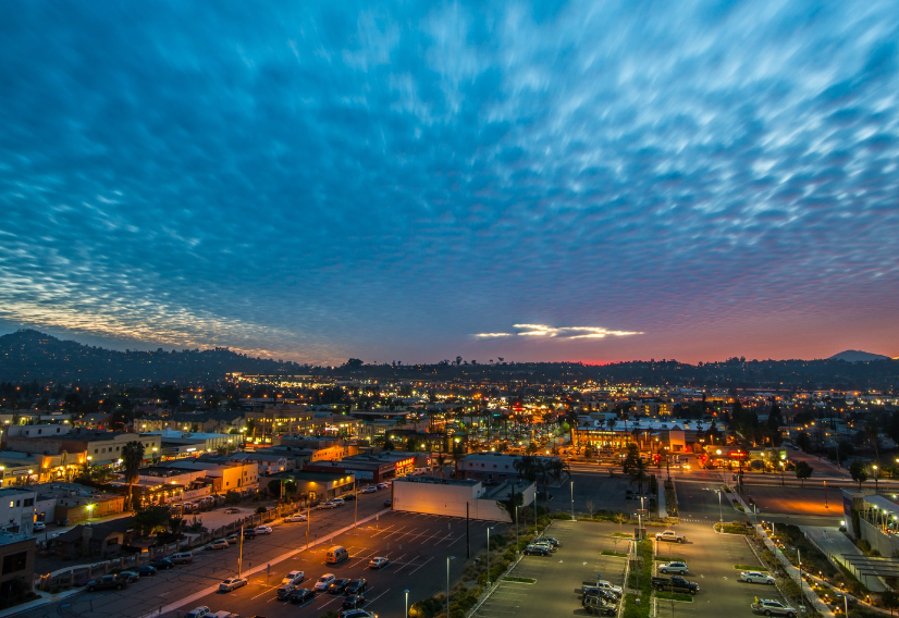 An aerial view of a city at sunset with a parking lot in the foreground.