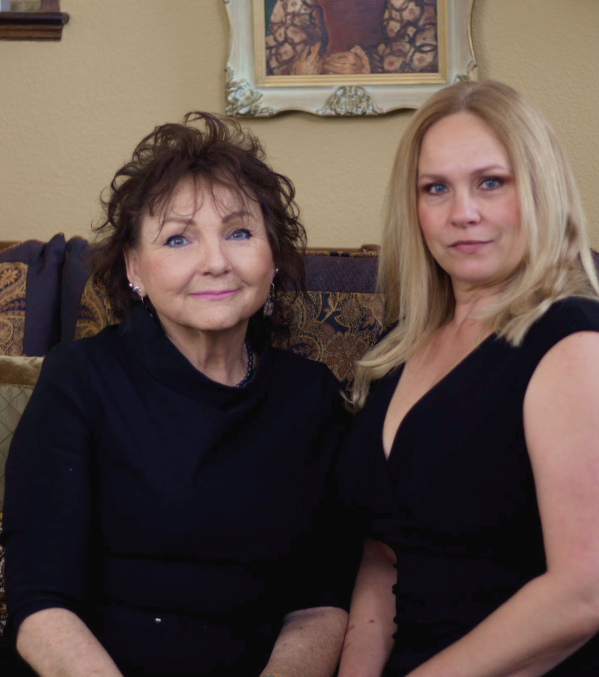 Two women are posing for a picture while sitting on a couch