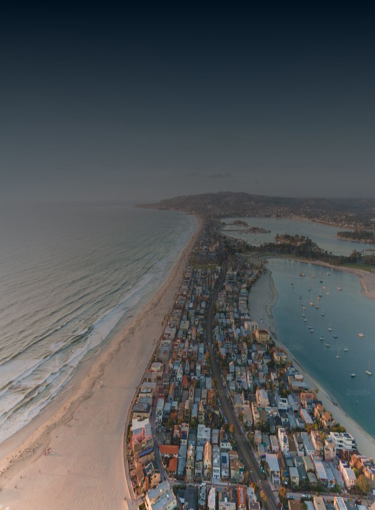 An aerial view of a city next to a beach at night.