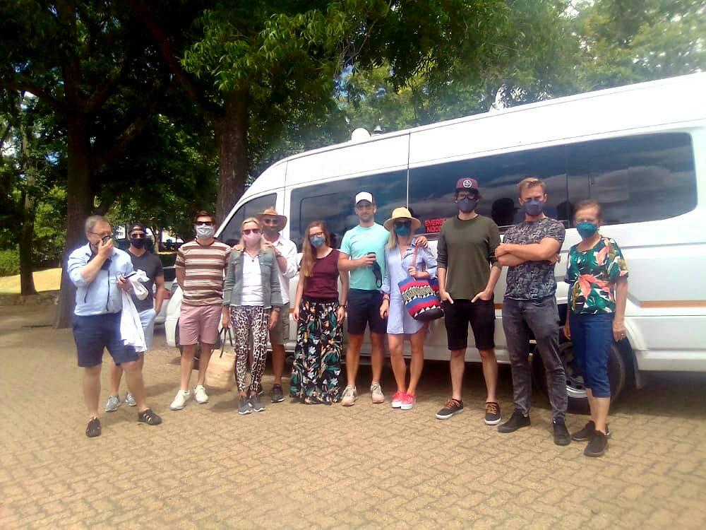A group of people wearing masks are standing in front of a white van.