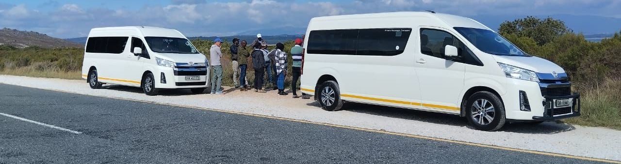 A group of white vans are parked on the side of a road.