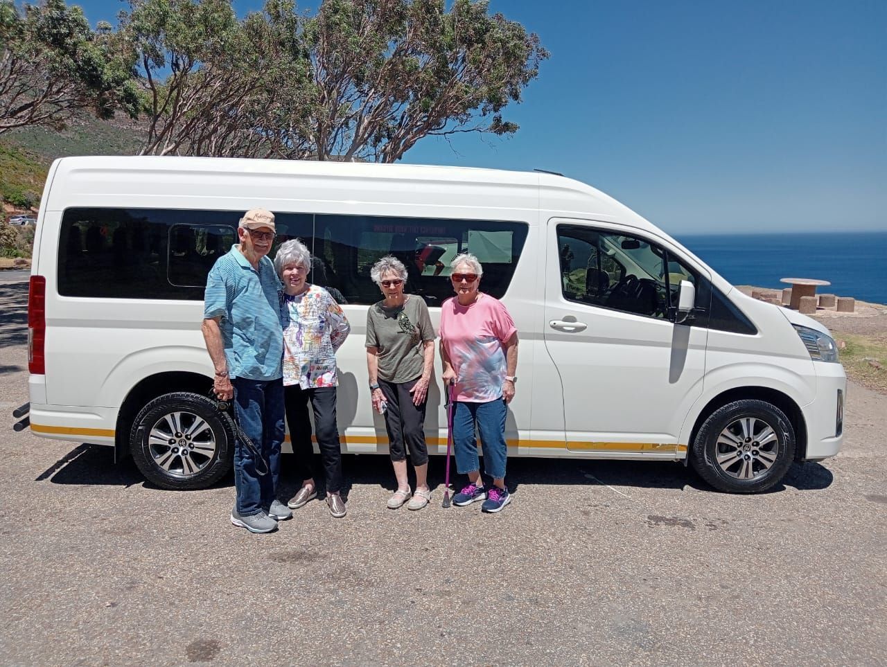 A group of people are posing for a picture in front of a white van.
