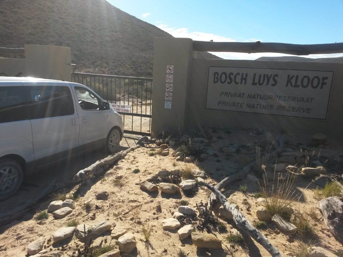 A white van is parked in front of a sign that says bosch luys kloof